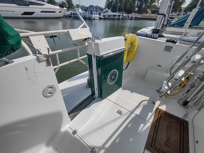 Slide: The Image of 2003 American Tug 34 boat deck with marina view, featuring safety equipment and welcome mat. - 12