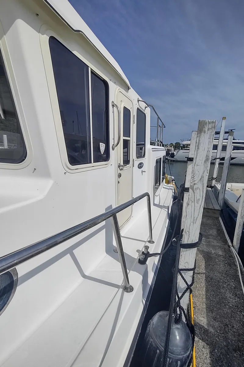 Slide: The Image of 2003 American Tug 34 docked, side view with railing and windows. - 14