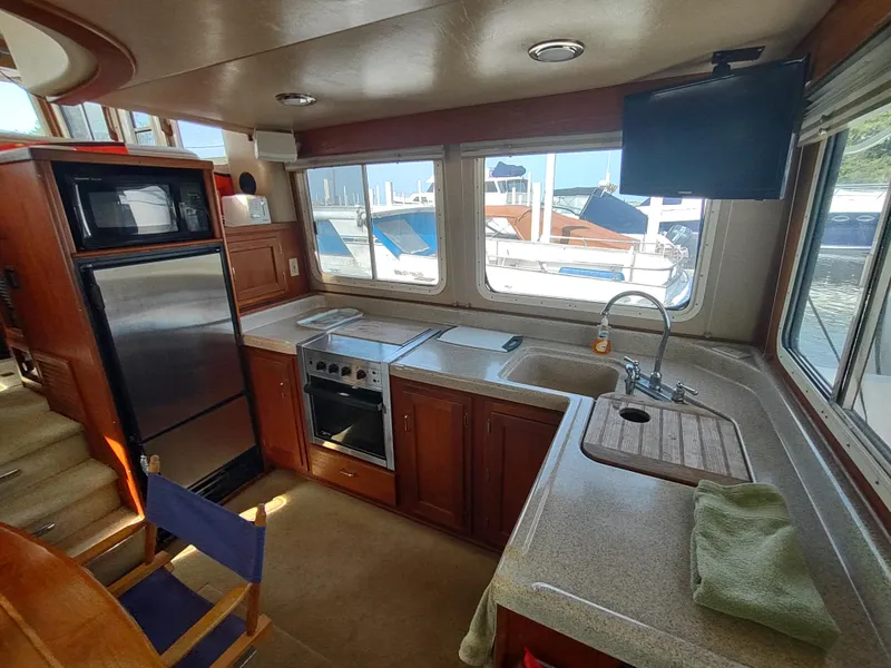 Slide: The Image of Interior of 2003 American Tug 34 with kitchen, appliances, and marina view through windows. - 15