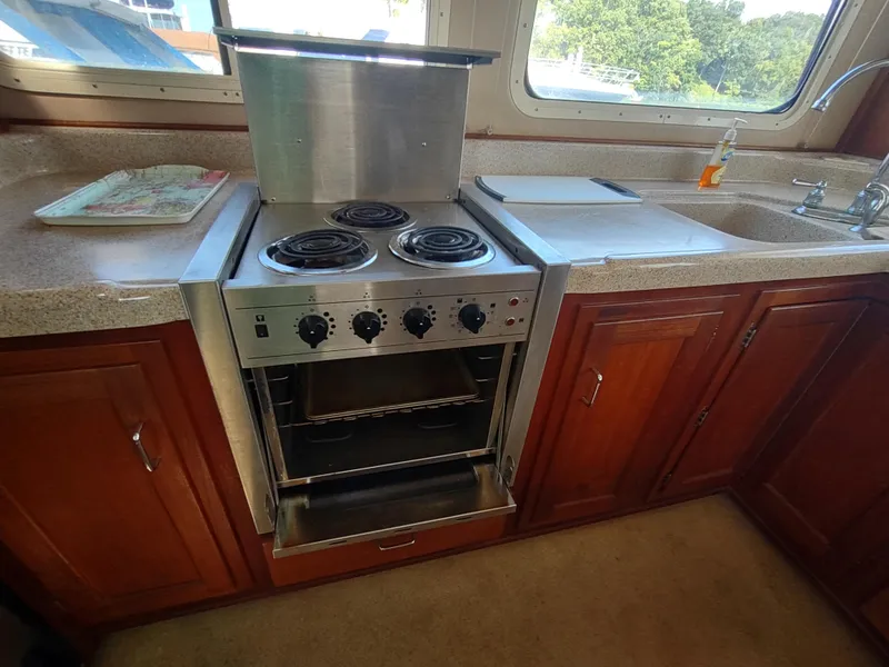 Slide: The Image of Kitchen area in a 2003 American Tug 34 with stove and wooden cabinets. - 16