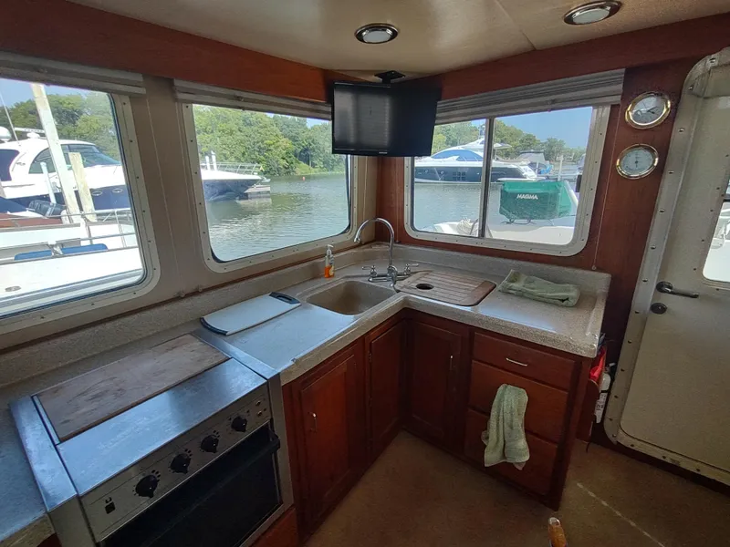 Slide: The Image of Interior of 2003 American Tug 34, featuring a compact kitchen with windows and appliances. - 17