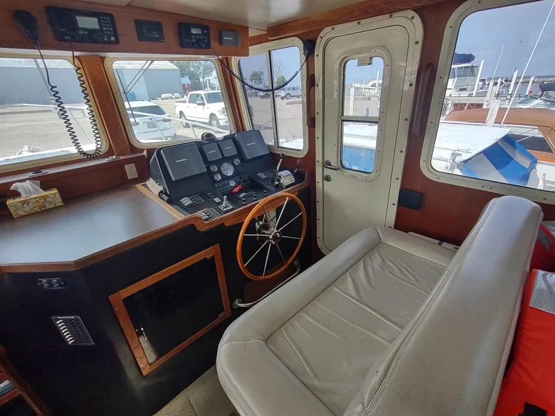 Slide: The Image of Pilothouse interior of 2003 American Tug 34, featuring navigation equipment and seating. - 23