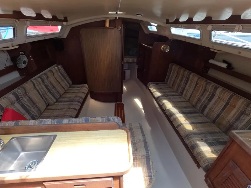 Slide: The Image of Interior of a 1985 Catalina 30 sailboat with plaid seating and wooden cabinetry. - 11