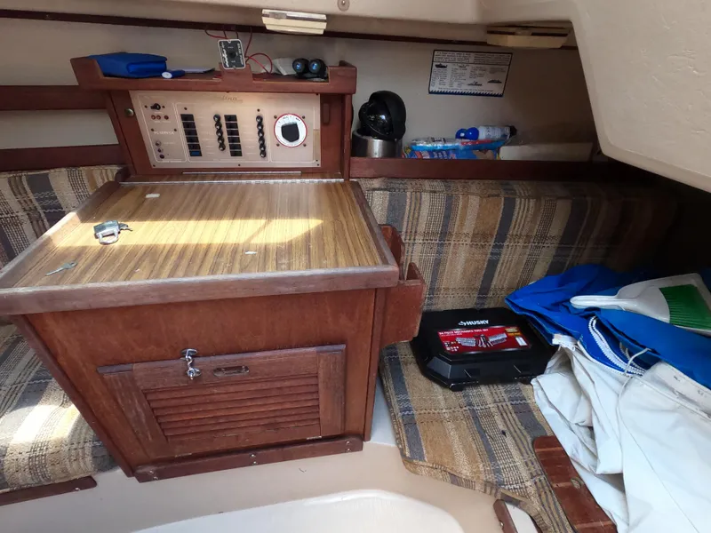 Slide: The Image of Interior of a 1985 Catalina 30 sailboat with wooden cabinetry and plaid seating. - 12