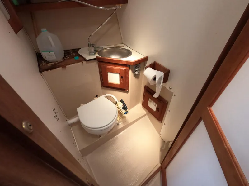 Slide: The Image of 1985 Catalina 30 boat bathroom with toilet, sink, and wooden accents. - 16