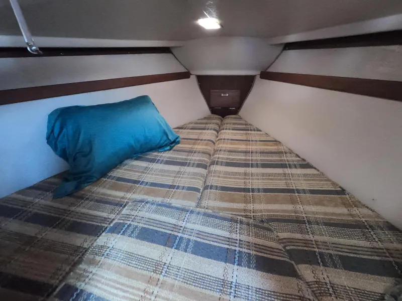 Slide: The Image of Cozy cabin interior of a 1985 Catalina 30 sailboat with plaid bedding and a blue pillow. - 17