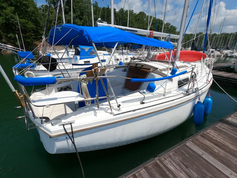 Slide: The Image of 1985 Catalina 30 sailboat docked, featuring blue and red covers, in a marina setting. - 5