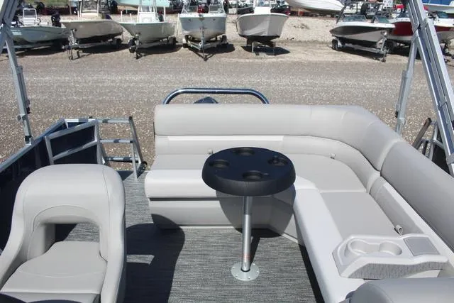 Slide: The Image of 2025 Godfrey Pontoons Xperience 1680 CX interior with seating and table, docked among other boats. - 7