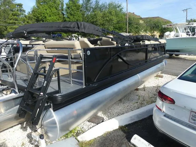 Slide: The Image of 2025 Godfrey Pontoons Sweetwater 2486 C, sleek black design, docked on gravel. - 4