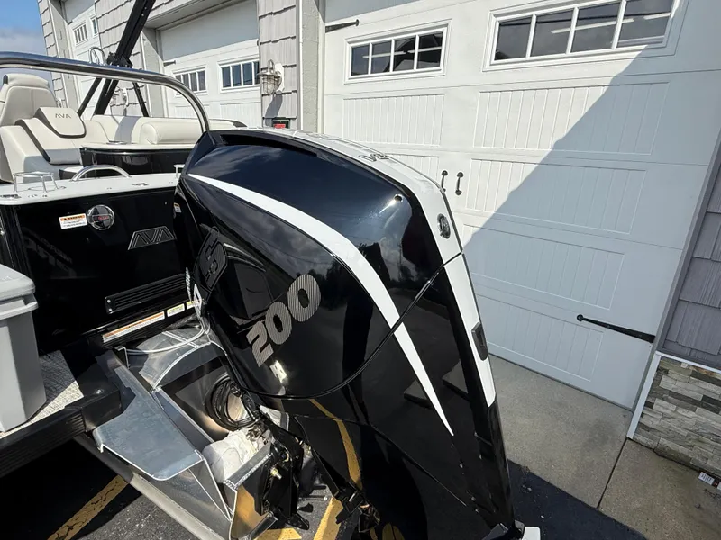 Slide: The Image of 2025 Avalon 2385 Catalina Quad Lounger with powerful outboard motor, parked near garage. - 10