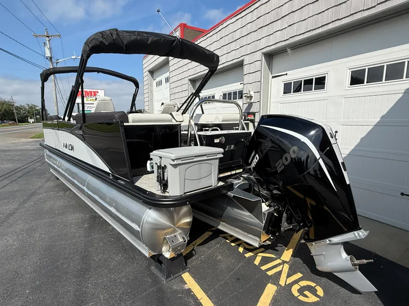 Slide: The Image of 2025 Avalon 2385 Catalina Quad Lounger Tri Toon boat parked outside a garage. - 8
