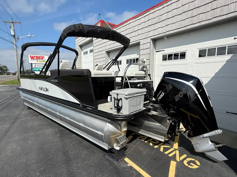 Slide: The Image of 2025 Avalon 2385 Catalina Quad Lounger Tri Toon boat parked outside a garage. - 9
