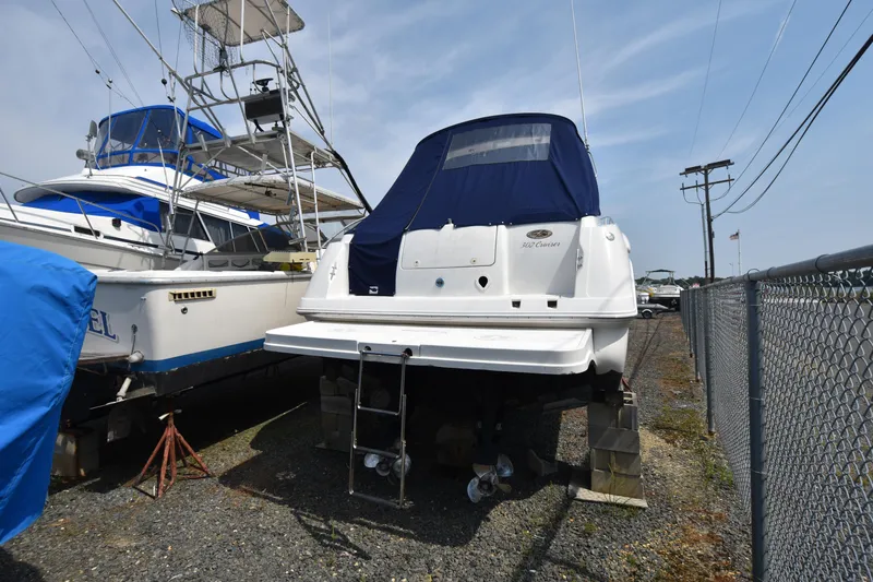 Slide: The Image of 2000 Monterey 302 Cruiser boat on blocks, covered, beside another vessel in a storage yard. - 4
