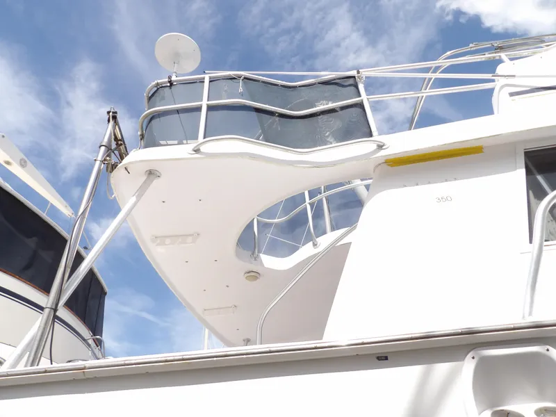 Slide: The Image of 1999 Mainship 350 Trawler, white exterior, upper deck view against blue sky. - 11