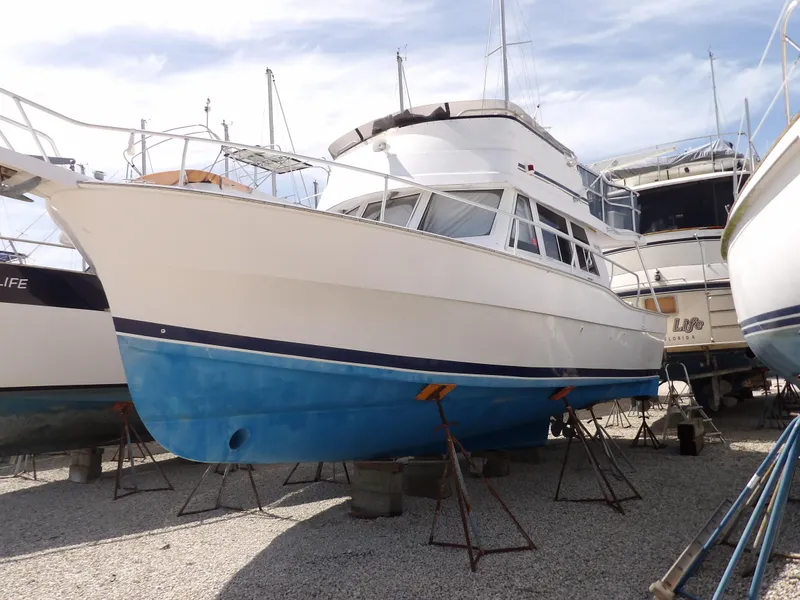Slide: The Image of 1999 Mainship 350 Trawler with blue hull, docked on land. - 2