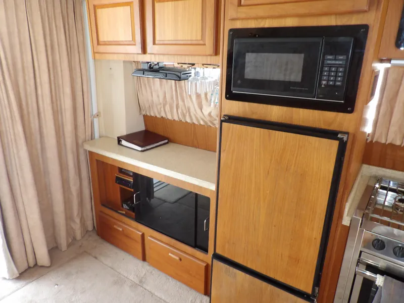 Slide: The Image of 1999 Mainship 350 Trawler kitchen with wood cabinets, microwave, and fridge. - 35