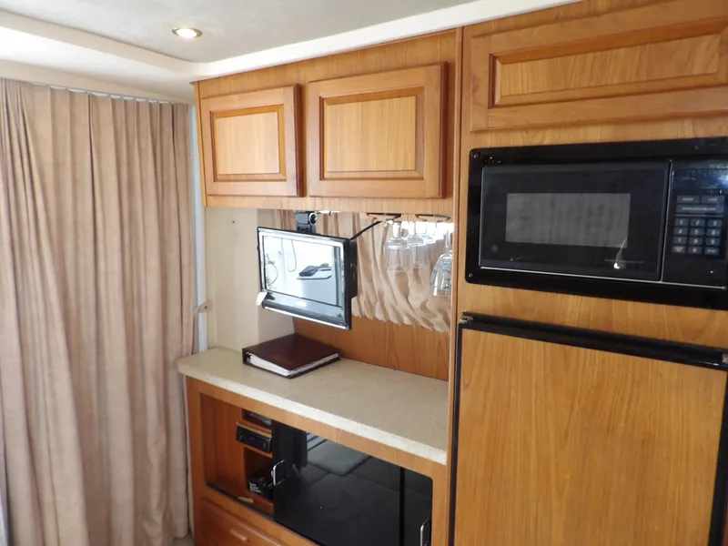 Slide: The Image of 1999 Mainship 350 Trawler interior with wood cabinets, microwave, and small TV. - 36