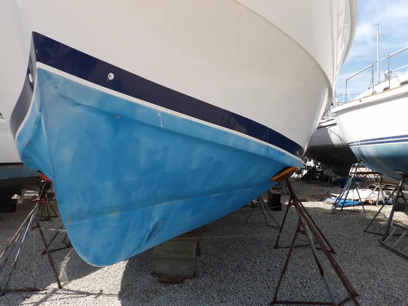 Slide: The Image of 1999 Mainship 350 Trawler on stands, blue hull, gravel ground. - 4