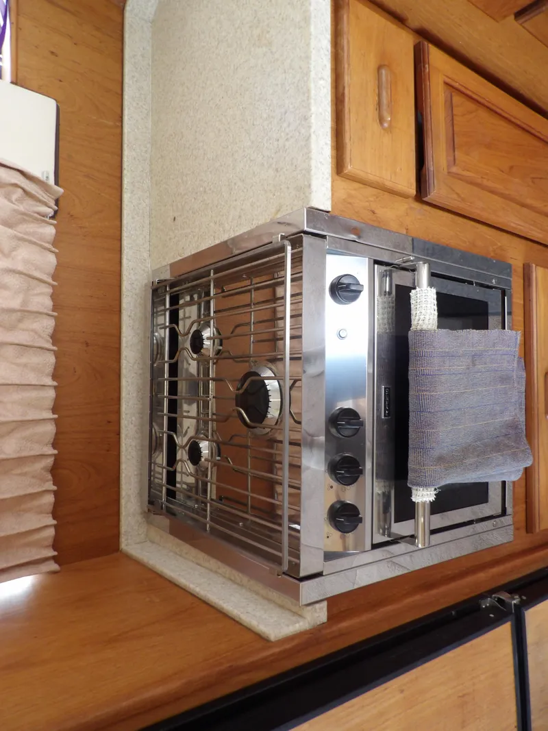 Slide: The Image of 1999 Mainship 350 Trawler kitchen with stainless steel stove and wooden cabinetry. - 40