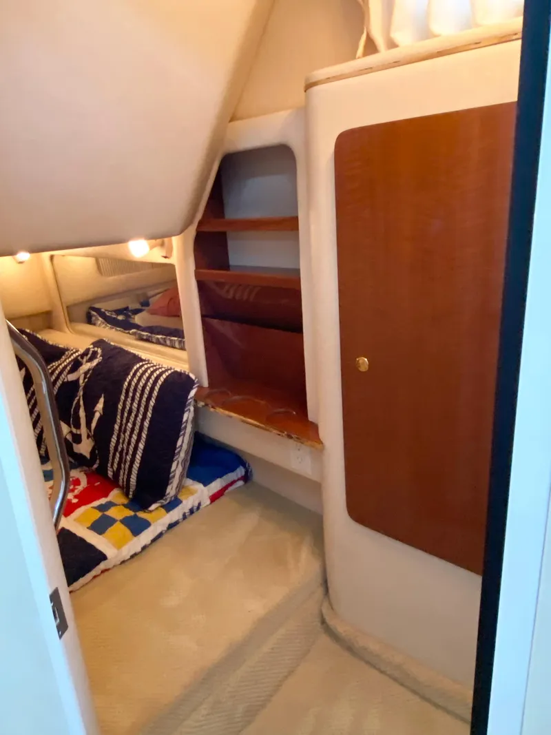 Slide: The Image of 2001 Sea Ray 290 Sundancer cabin interior with cozy bedding and wooden storage. - 17