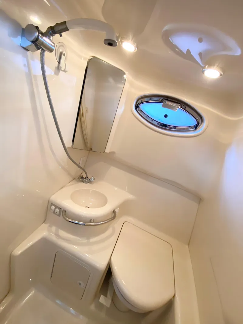 Slide: The Image of 2001 Sea Ray 290 Sundancer bathroom with shower, sink, and porthole window. - 8