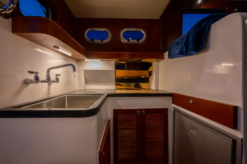 Slide: The Image of 2024 SeaPiper 37 yacht interior kitchen with sink, cabinets, and porthole windows. - 6