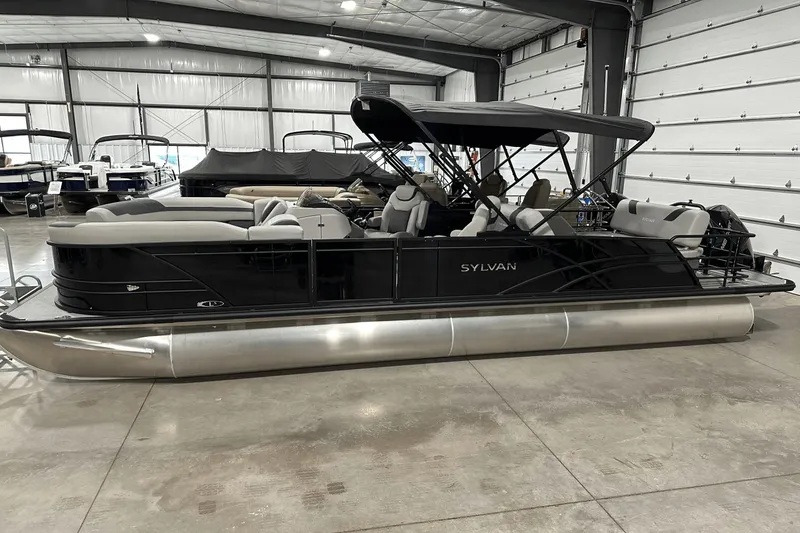 Slide: The Image of 2025 Sylvan L-5 pontoon boat in showroom, featuring sleek design and spacious seating. - 10