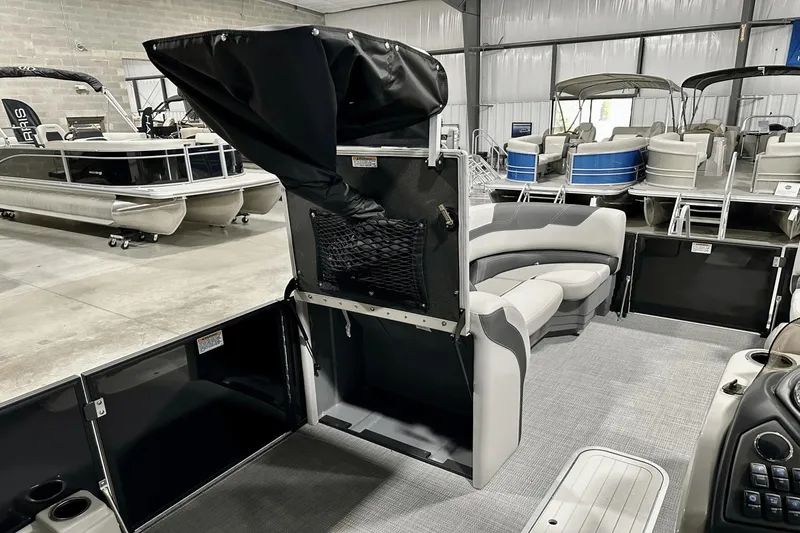Slide: The Image of 2025 Sylvan L-5 pontoon boat interior with seating and storage, displayed in a showroom. - 23