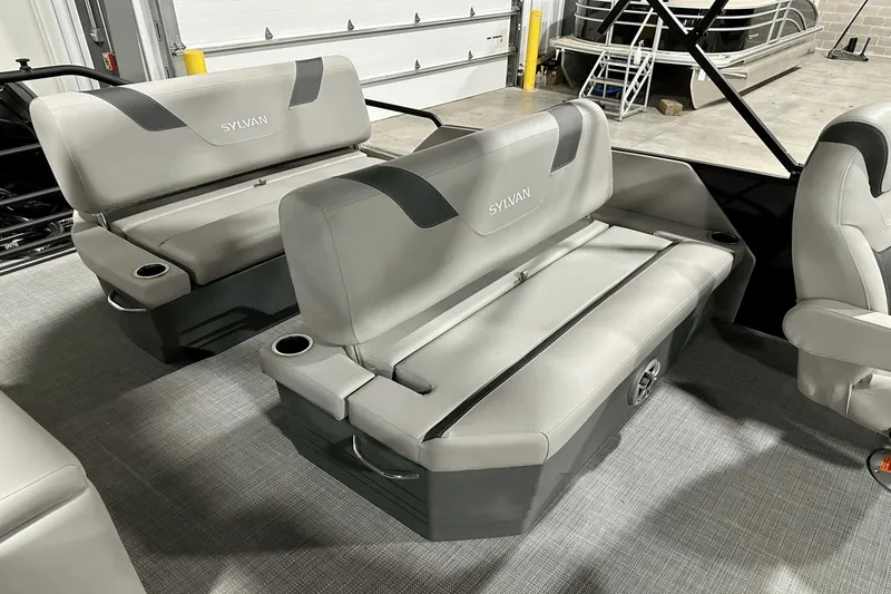 Slide: The Image of 2025 Sylvan L-5 boat interior with gray seating and cup holders in a showroom. - 33