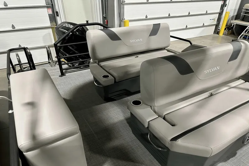 Slide: The Image of 2025 Sylvan L-5 boat interior with gray seating and cup holders in a garage setting. - 34