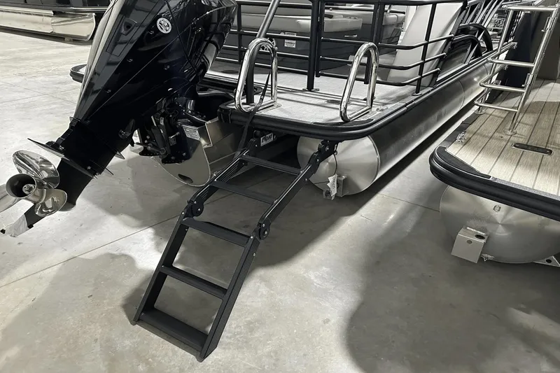 Slide: The Image of 2025 Sylvan L-5 pontoon boat with outboard motor and boarding ladder in a showroom. - 9