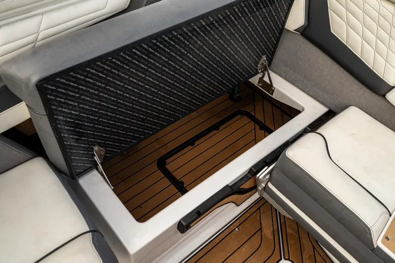 Slide: The Image of 2022 Nautique Super Air Nautique G23 storage compartment with open lid and cushioned seating. - 23