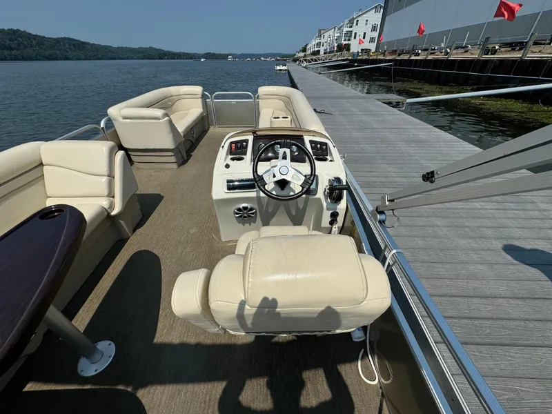 Slide: The Image of 2014 Bennington 24 SLX3 pontoon boat interior with beige seating, docked by a wooden pier. - 10