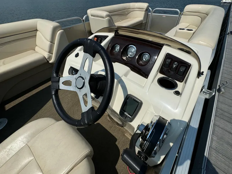 Slide: The Image of 2014 Bennington 24 SLX3 boat interior with steering wheel and seating, docked by the water. - 11