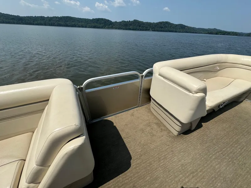Slide: The Image of 2014 Bennington 24 SLX3 pontoon boat interior with beige seating on a calm lake. - 19