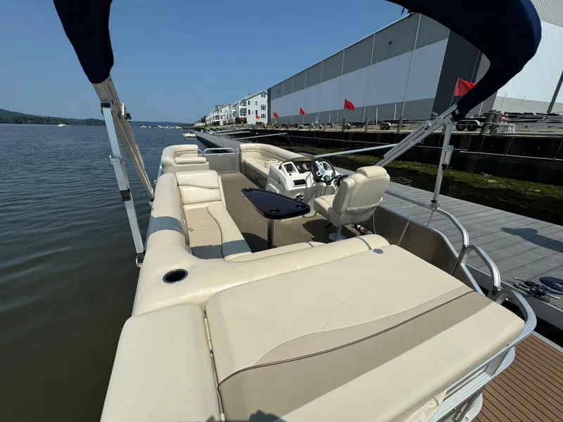 Slide: The Image of 2014 Bennington 24 SLX3 pontoon boat with beige seating, docked by a waterfront building. - 8