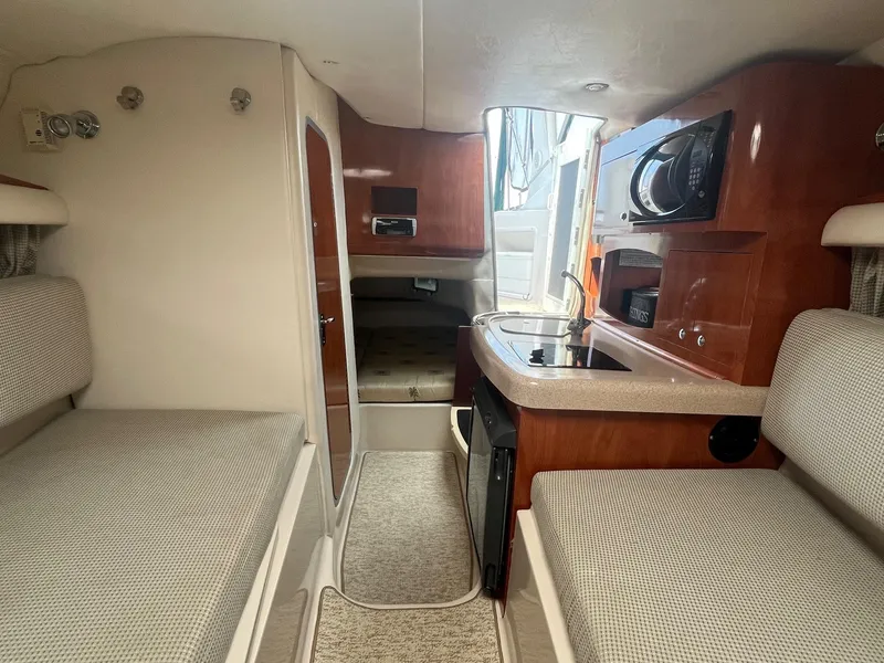 Slide: The Image of Interior of 2006 Four Winns 278 Vista boat, featuring cozy seating and compact kitchen area. - 16