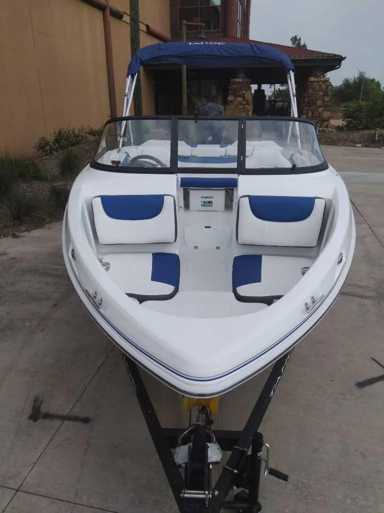 Slide: The Image of 2024 Tahoe 200 S boat with blue and white seating, docked outdoors. - 1