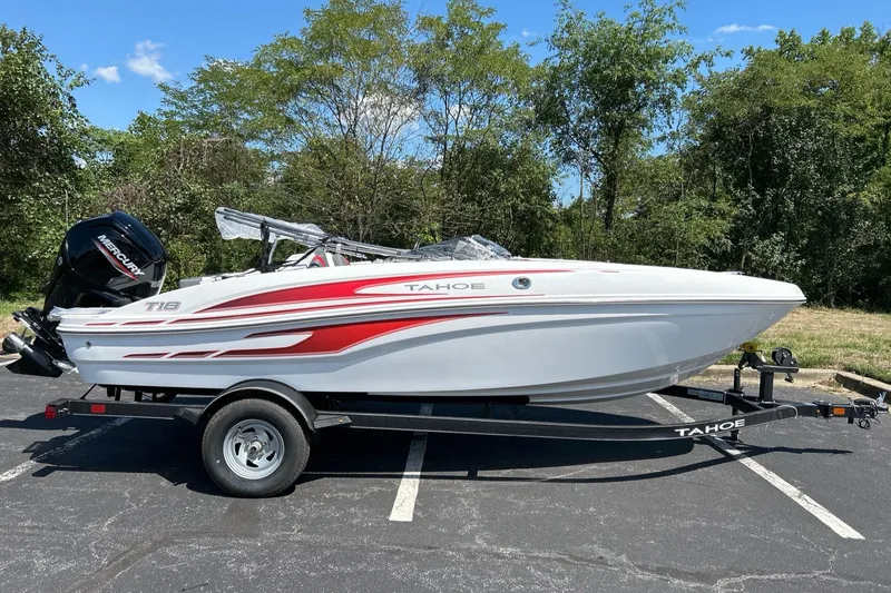 Slide: The Image of 2024 Tahoe T18 boat on trailer, white with red accents, parked outdoors. - 2