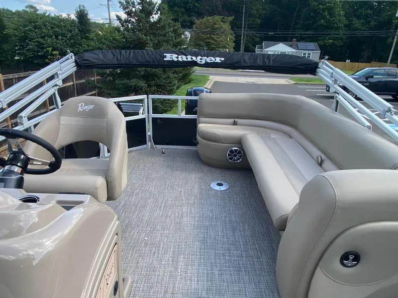 Slide: The Image of 2024 Ranger Reata 200C pontoon boat interior with beige seating and steering wheel. - 5
