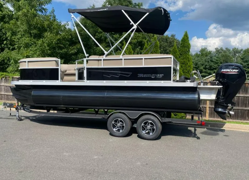 Slide: The Image of 2024 Ranger Reata 200C pontoon boat with canopy on trailer, parked outdoors. - 9