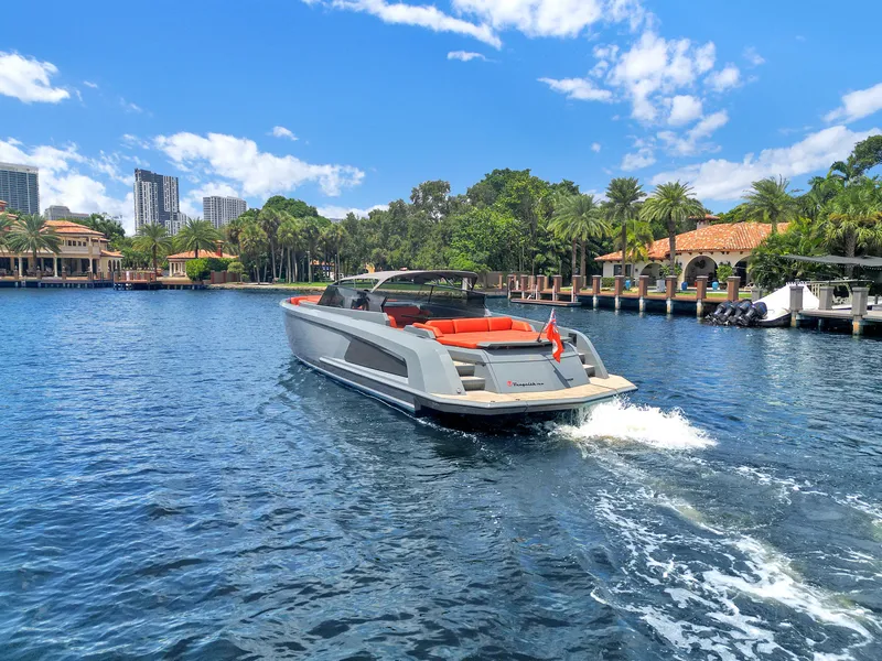 Slide: The Image of Vanquish Yachts VQ 54 cruising on a sunny day, surrounded by lush greenery and waterfront homes. - 20