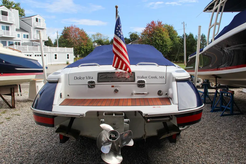 Slide: The Image of 2004 Chris-Craft Launch 25 boat with American flag, docked on gravel. - 3