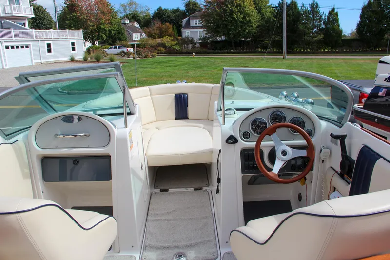 Slide: The Image of 2004 Chris-Craft Launch 25 boat interior with white seating and wooden steering wheel. - 32