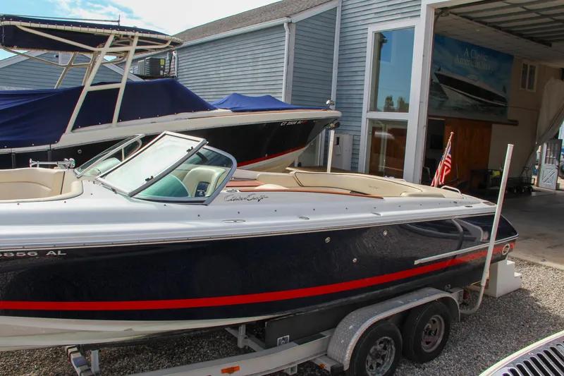 Slide: The Image of 2004 Chris-Craft Launch 25 boat on trailer, parked near a boathouse. - 42