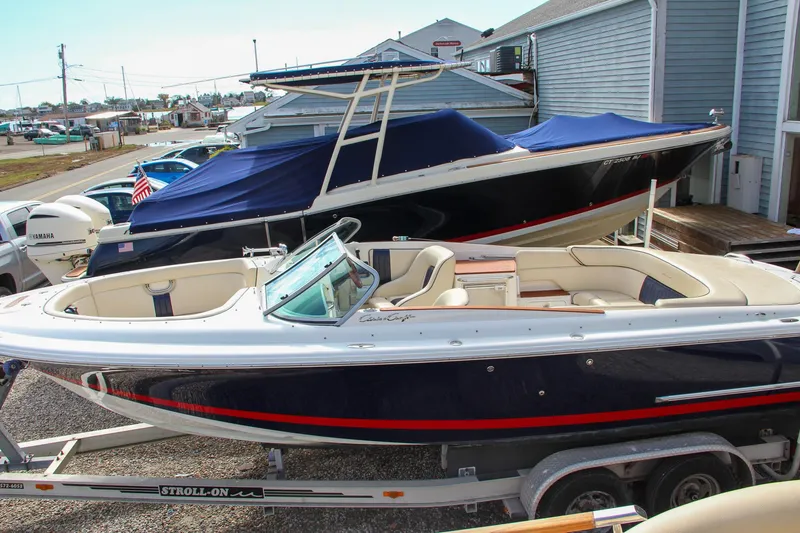 Slide: The Image of 2004 Chris-Craft Launch 25 boat on trailer, navy blue hull, parked near marina. - 43