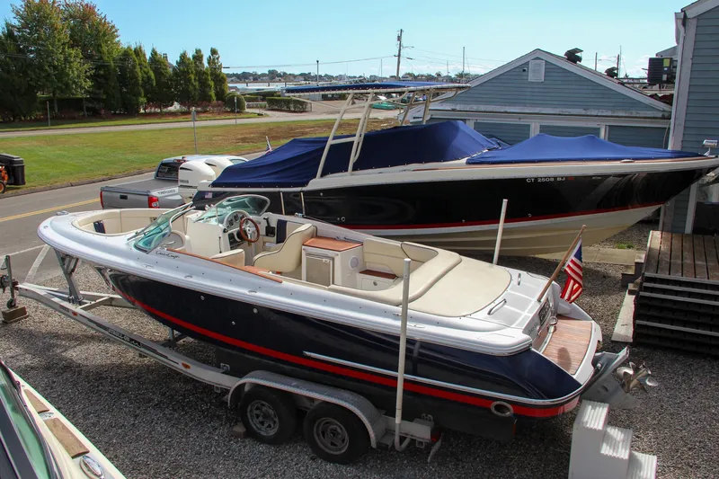 Slide: The Image of 2004 Chris-Craft Launch 25 boat on trailer, parked outdoors near another boat. - 44