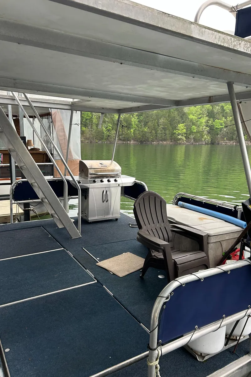 Slide: The Image of 1988 Waterhouse houseboat with catwalks, featuring outdoor seating and grill, on a serene lake. - 11
