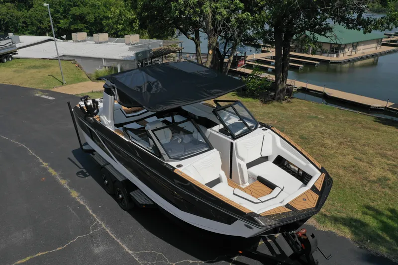 Slide: The Image of 2025 Nautique G23 boat on trailer near a lakeside dock. - 12