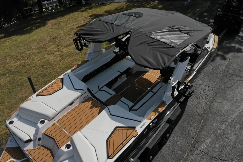 Slide: The Image of 2025 Nautique G23 boat with covered seating and teak deck, parked on pavement. - 14